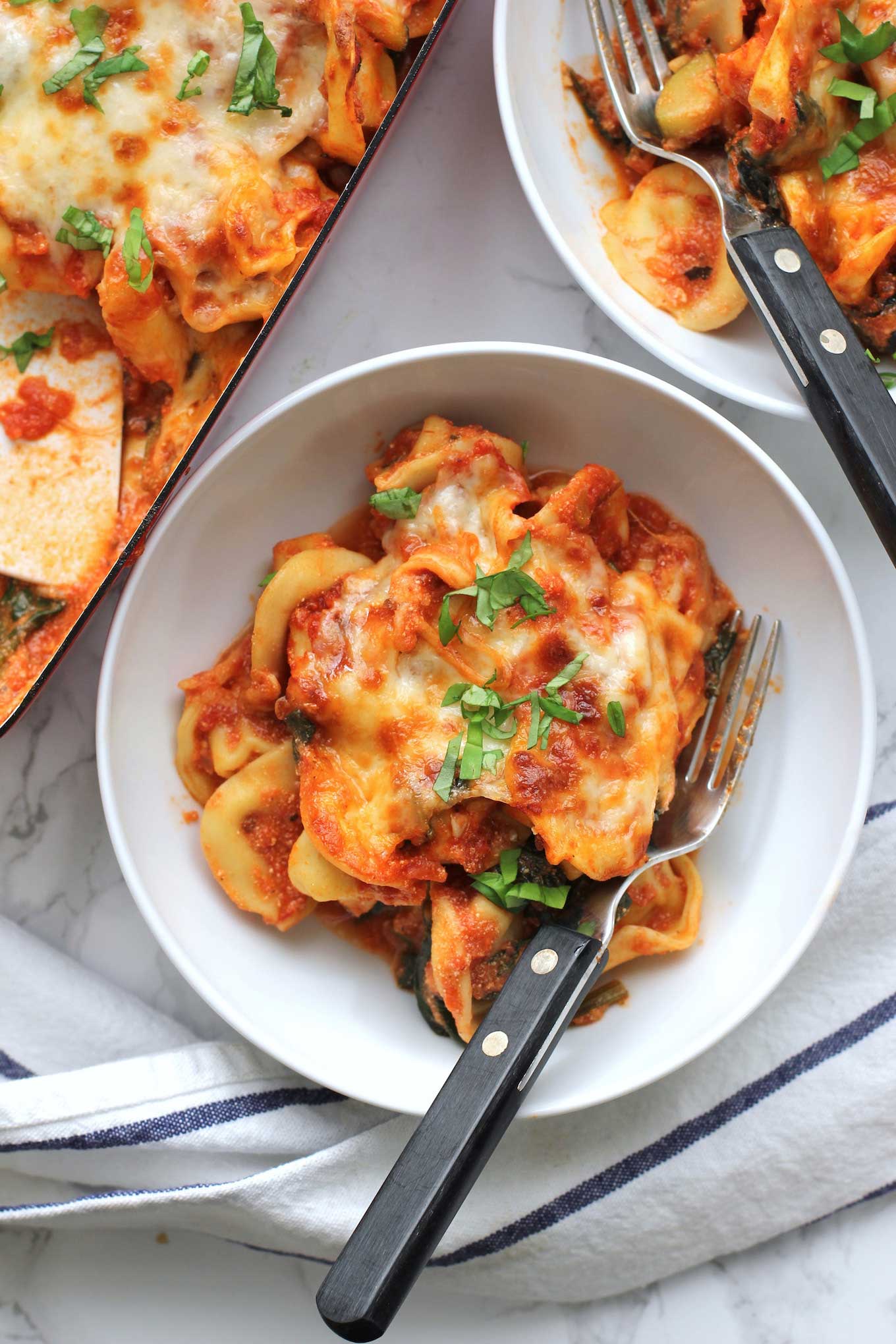 Baked Tortellini in a white bowl with a fork.