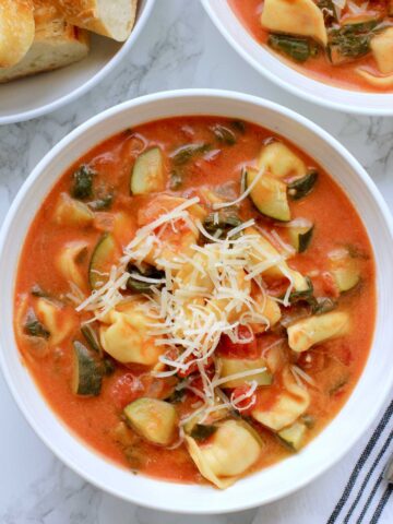 Tomato Tortellini Soup with Vegetables in a white bowl topped with cheese