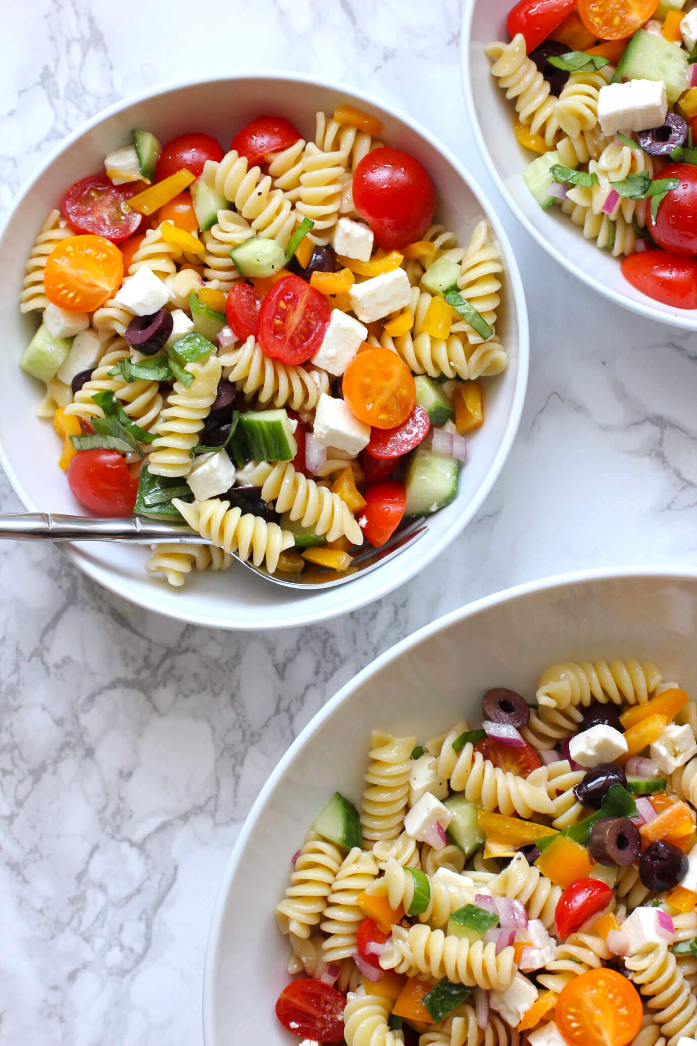 Greek pasta salad in a white bowl with a fork.