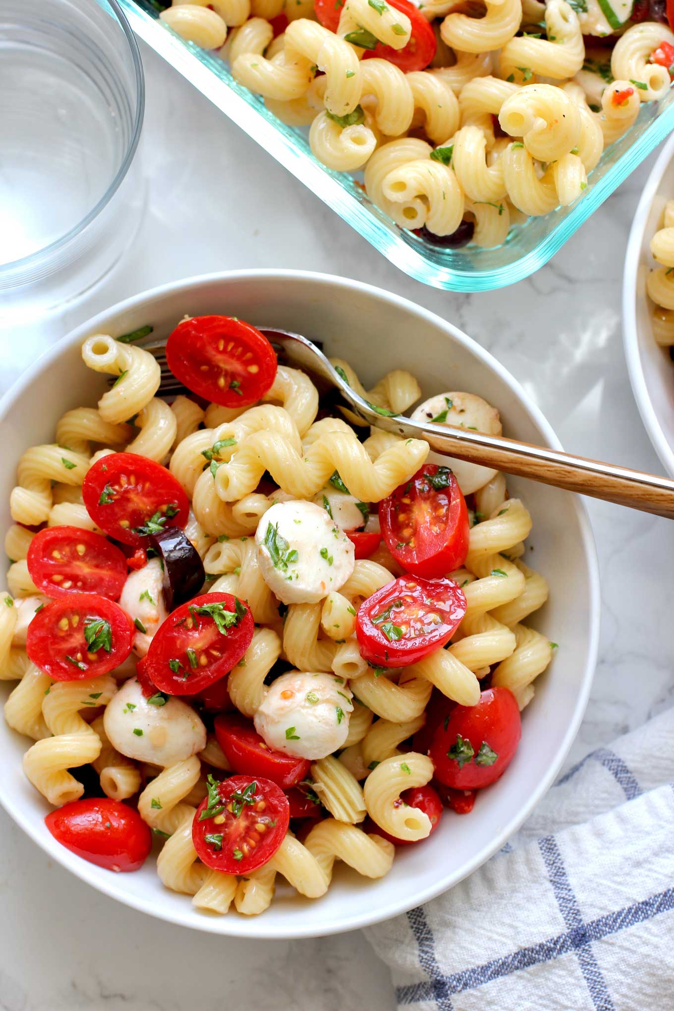 Close up view of white bowl with pasta salad and a fork.